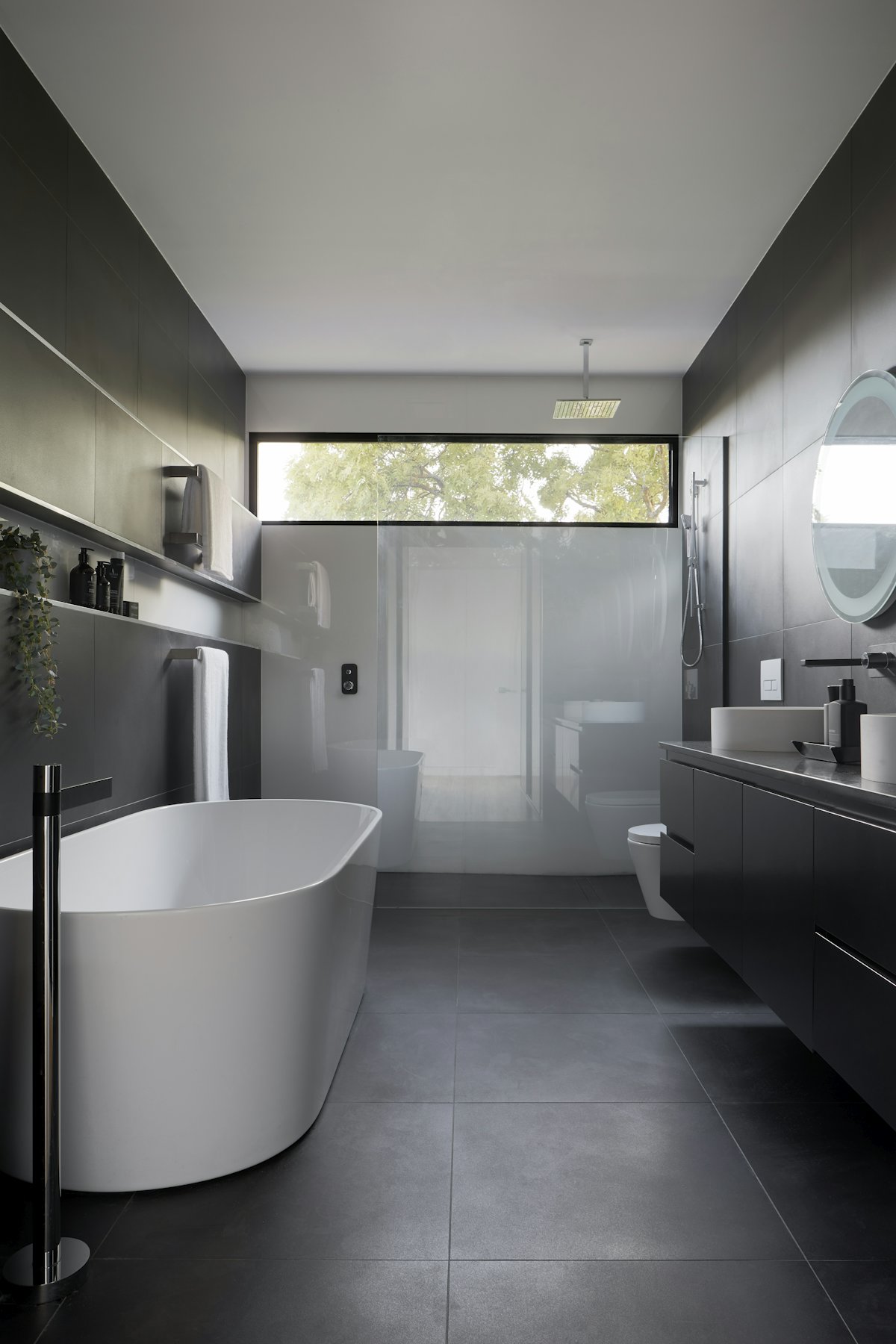Modernes Badezimmer mit freistehender Wanne und dunklem Fliesenboden