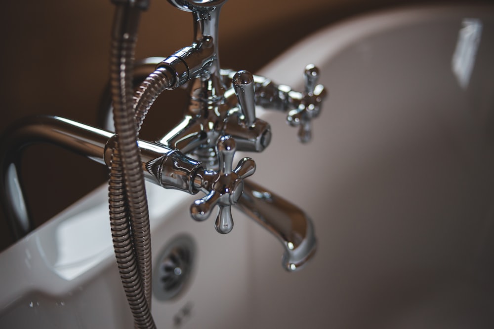 Verchromte Wannenarmatur mit Brauseschlauch an einer Badewanne