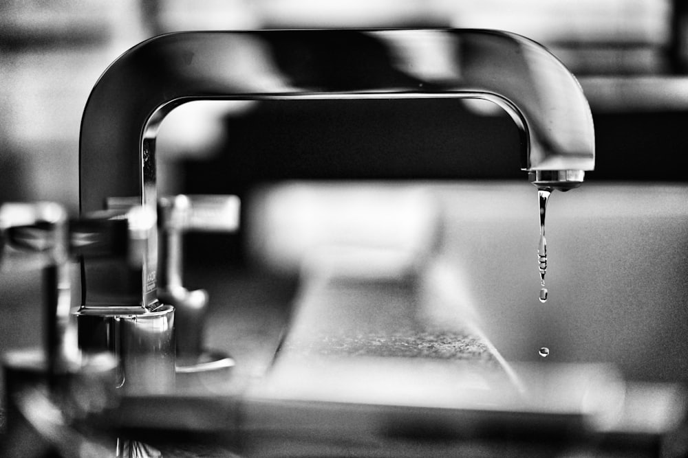 Nahaufnahme einer Chromarmatur, aus der ein Wassertropfen fällt